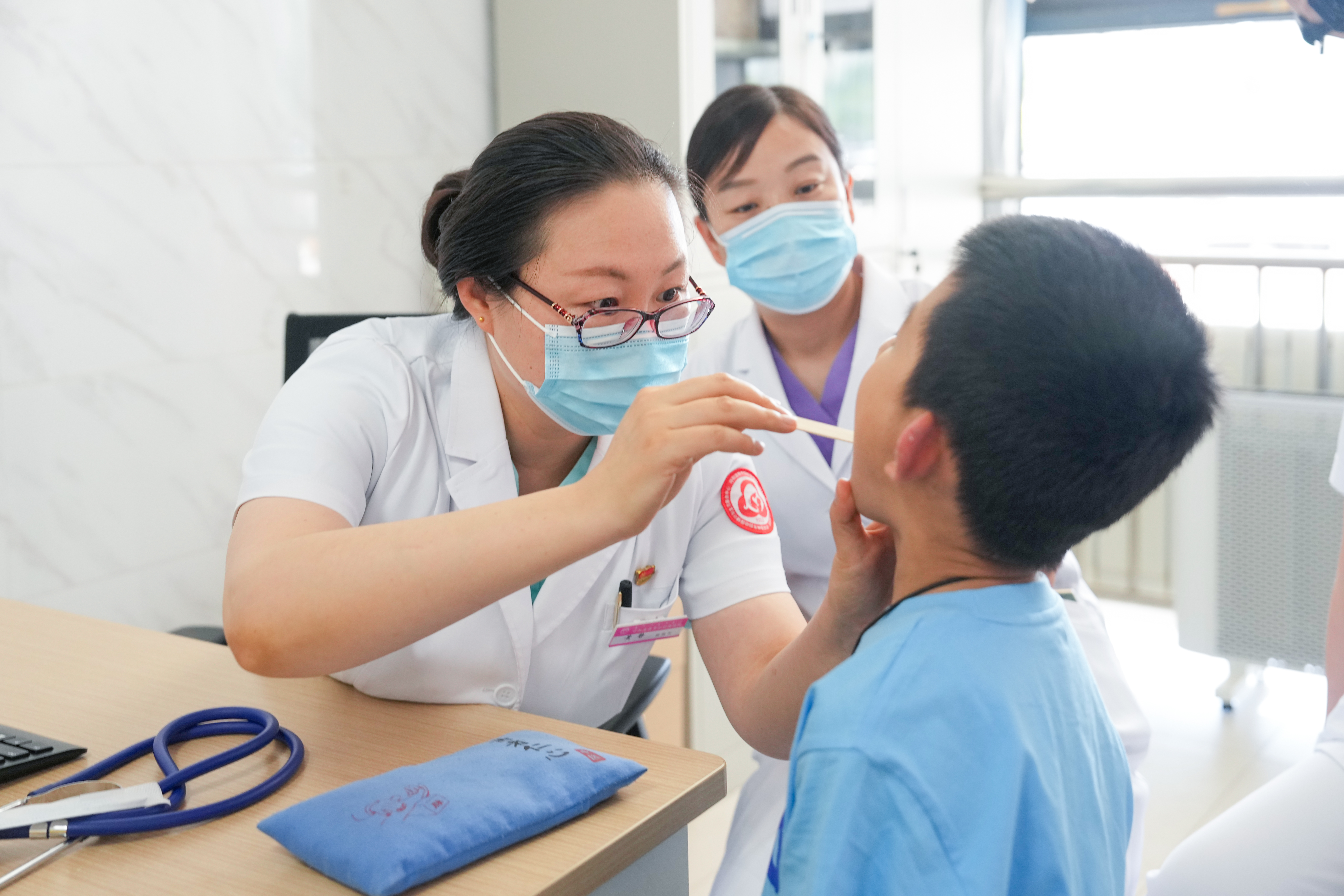 在呼和浩特市婦幼保健院中醫兒科門診，掛職副院長黃靜（左一）在細查看患兒咽喉情況。