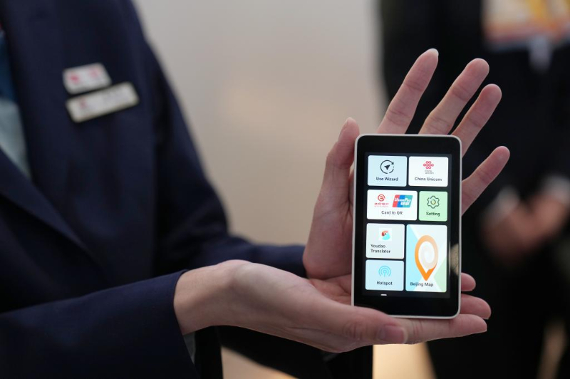 在北京首都國際機場T3航站樓的“北京服務”機場服務點，一位工作人員在展示“兩卡融合”終端。