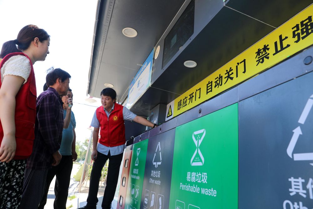 在安徽省合肥市長豐縣莊墓鎮棗林社區，誌願者指導居民使用智能垃圾分類回收設備（2023年9月1日攝）。
