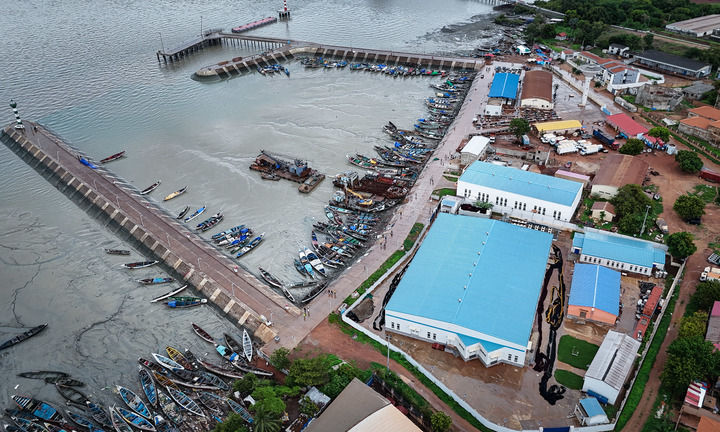這是2024年7月8日在幾內亞比紹首都比紹拍攝的板丁漁業碼頭和中企投建的水產品加工存儲綜合設施（右側藍頂建築區域）（無人機照片）。
