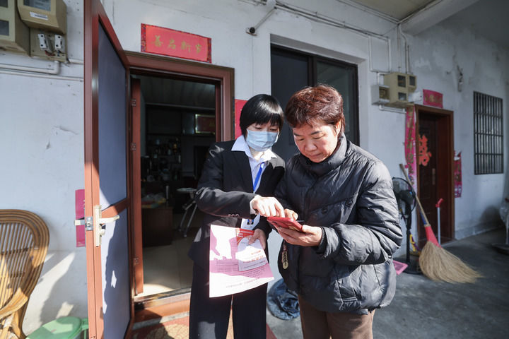 2025年12月18日，浙江省諸暨市東白湖鎮事業綜合服務中心的黨員誌願者（左）上門“一對一”指導村民使用“浙裏辦”數字化平台辦理業務。