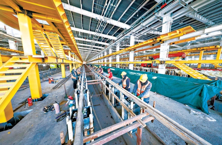 在軌道交通22號線平房停車場施工現場，工人們在運用庫裏鋪設軌道，現場忙得熱火朝天。