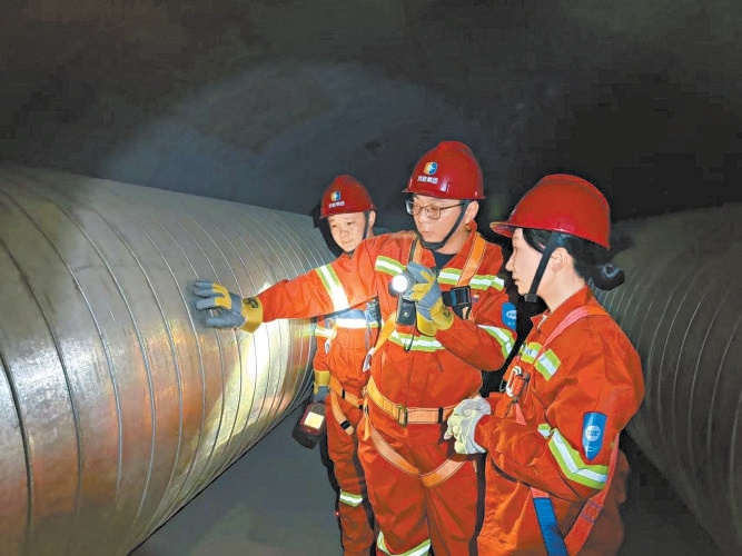 熱力人員下井巡查管網，本報記者張楠（右一）隨同采訪。