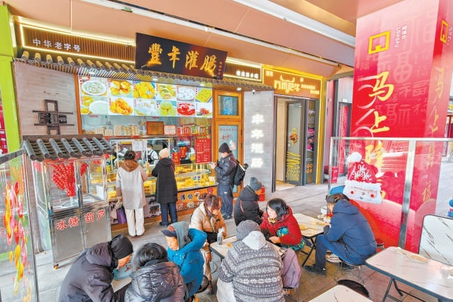 2月12日，在隆福寺豐年灌腸店鋪，市民遊客品嚐北京特色小吃。