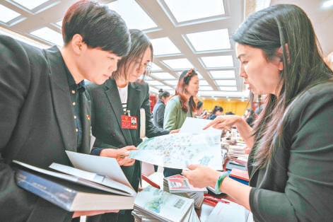 1月24日晚上，市人大代表詢問、政協委員谘詢活動在北京會議中心舉行。在市文化和旅遊局谘詢台，工作人員在向杜岩代表（左）、魏雪代表（中）介紹旅遊休閑綠道建設。